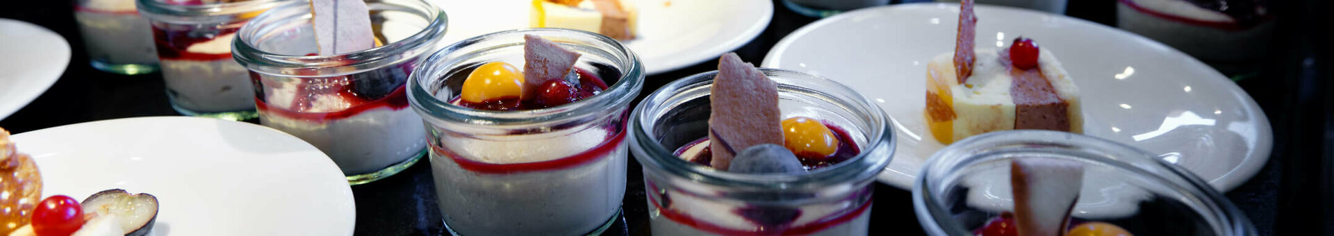 Dessert buffet with fresh fruit and small glasses of panna cotta, decorated with berries and pastries at the ATLANTIC Hotel.