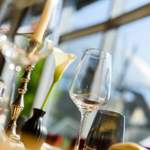 Eingedeckter Tisch im Restaurant | Restaurant CAMPUS im ATLANTIC Hotel Universum Eleganter Tisch mit Weinglas, Kerze und Blume, im ATLANTIC Hotel Universum Bremen.