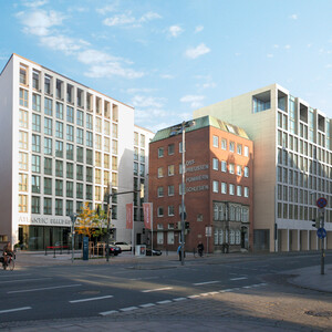 Modern hotel building on a street corner in daylight, with glass facades and surrounding buildings.