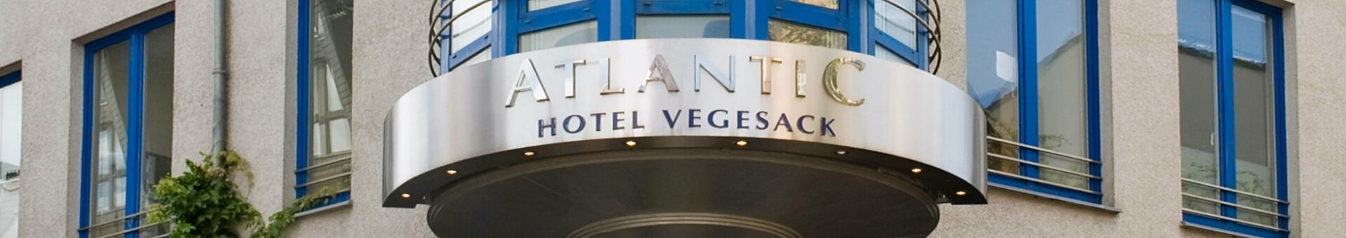 Entrance to the ATLANTIC Hotel Vegesack with round canopy and blue windows.