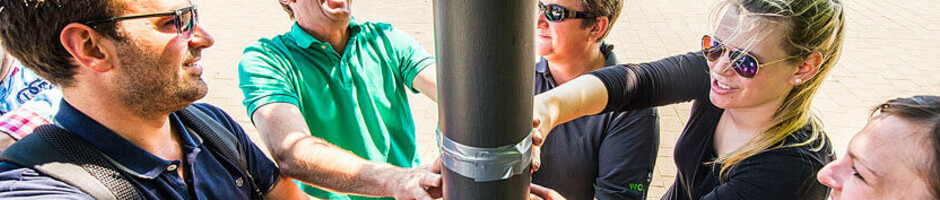 Eine Gruppe lachender Menschen steht am Kai in Kiel und fasst gemeinsam eine Laterne an.