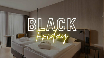 Modernes Hotelzimmer mit Doppelbett, Schreibtisch, Sessel, großem Fenster; Text: "Black Friday".