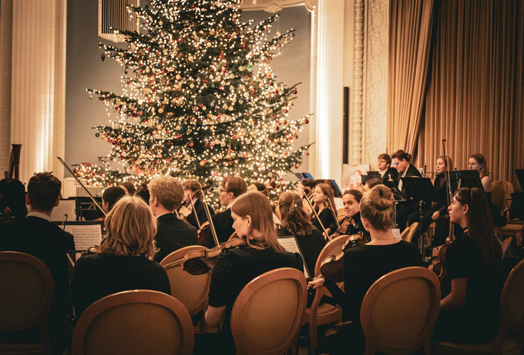 Orchester spielt vor einem festlich geschmückten Weihnachtsbaum im ATLANTIC Grand Hotel Travemünde.