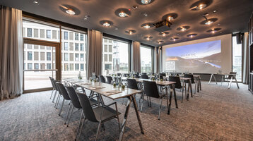 ATLANTIC Hotel Heidelberg Conference Modern conference room at the ATLANTIC Hotel Heidelberg with tables, chairs and a large screen.