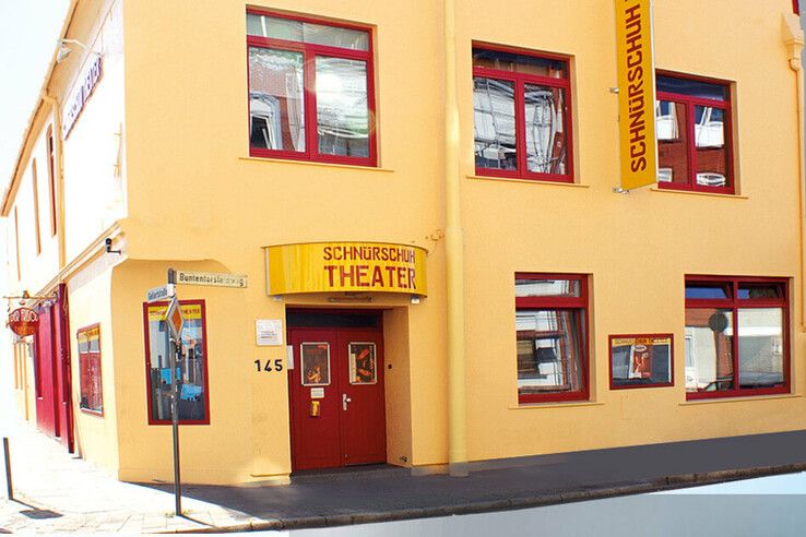 Yellow building with red entrance and windows, labeled "Schnürschuh Theater", street sign "Buntentorsteinweg". Schnürschuh Theater Bremen