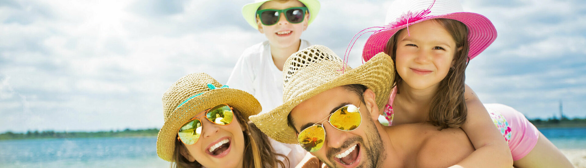 ATLANTIC Grand Hotel Travemünde – Familie am Strand © drubig photo – Fotolia Familie am Strand mit Sonnenhüten und Sonnenbrillen, lachend auf einer Luftmatratze liegend, Sandspielzeug im Vordergrund.
