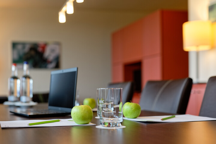 Studio for meetings  Modern conference room with laptop, apples, water bottles and writing materials on a wooden table in the ATLANTIC Hotel Bremen.