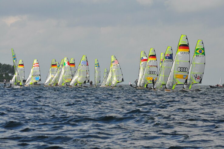 Sailing boats at a regatta on the Kiel Fjord under a cloudy sky.
