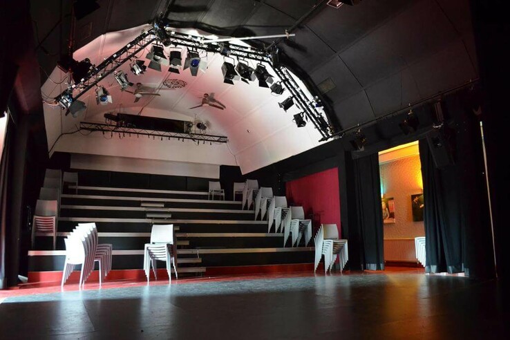 An empty, tiered event space with stacked chairs and professional lighting on the ceiling. Schnürschuh Theater Bremen.