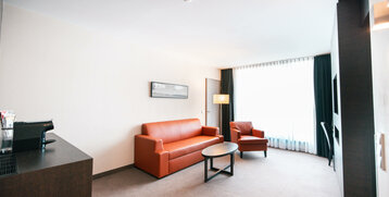 Wohnraum der Suite im ATLANTIC Hotel Lübeck mit Couch und Sessel