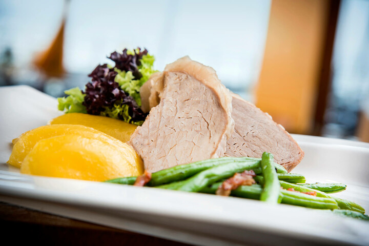 Gourmetgericht mit Schweinebraten, Kartoffeln, grünen Bohnen und Salat, serviert im ATLANTIC Hotel Sail City.
