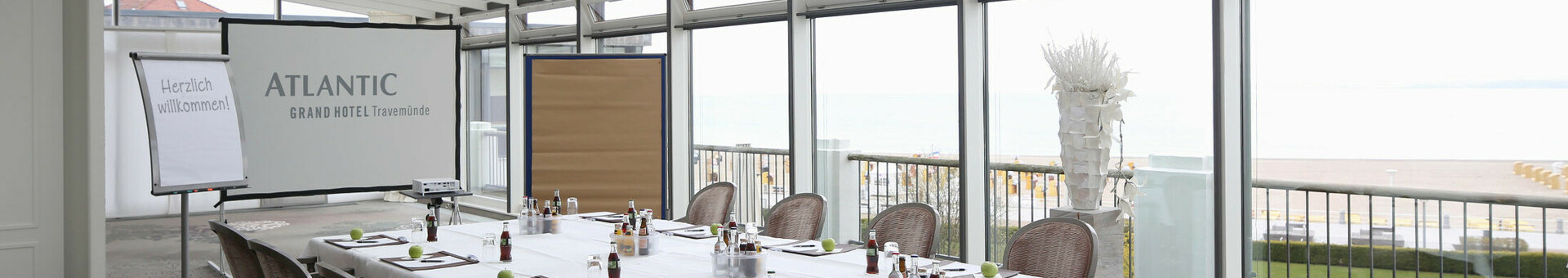 Konferenzraum mit Meerblick, gedeckter Tisch, Flipchart und Leinwand im ATLANTIC Grand Hotel Travemünde.