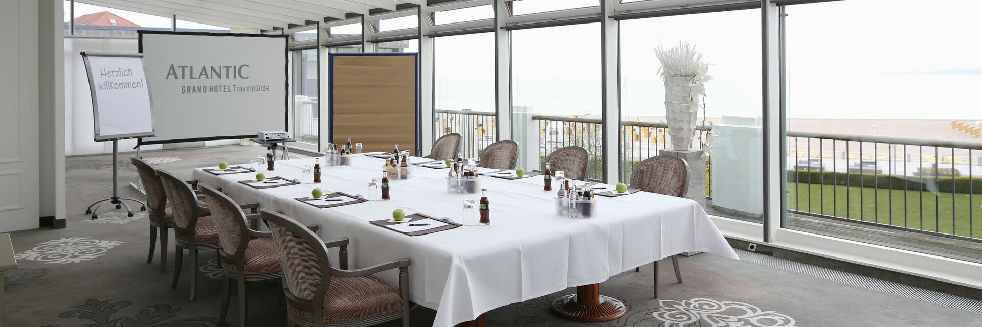 Konferenzraum mit Meerblick, gedeckter Tisch, Flipchart und Leinwand im ATLANTIC Grand Hotel Travemünde.