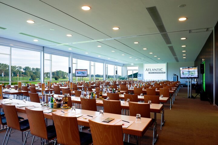 Auf über 1.000 qm bieten wir viel Platz für Tagungen, Kongresse und Messen Moderner Konferenzraum im ATLANTIC Hotel Galopprennbahn, Bremen, mit Tischen, Stühlen und Blick auf die Rennbahn.