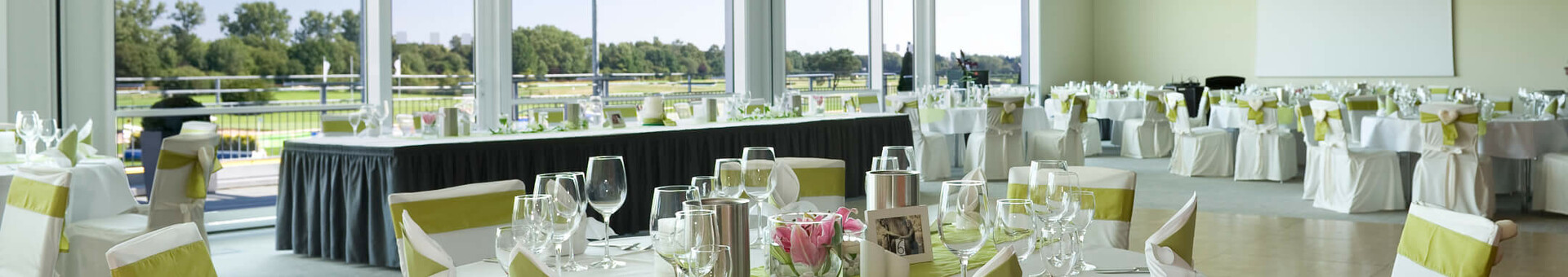 Elegant banquet hall in the ATLANTIC Hotel Galopprennbahn, Bremen, with set tables and a view of the racecourse.