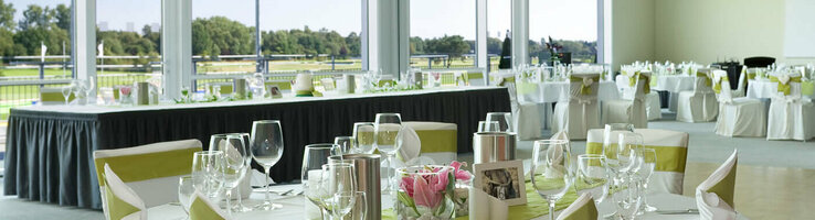 Elegant banquet hall in the ATLANTIC Hotel Galopprennbahn, Bremen, with set tables and a view of the racecourse.