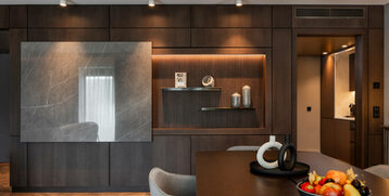 Elegantes Hotelzimmer mit dunklen Holzmöbeln, dekorativen Regalen und einem Tisch mit Obstschale im ATLANTIC Hotel Heidelberg.