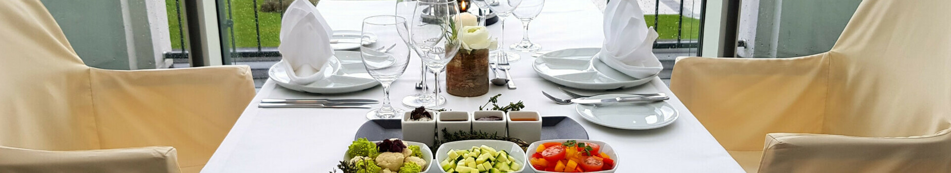 Offer ATLANTIC Fondue | ATLANTIC Grand Hotel Travemünde Elegant table setting at the ATLANTIC Grand Hotel Travemünde with a view of the garden.