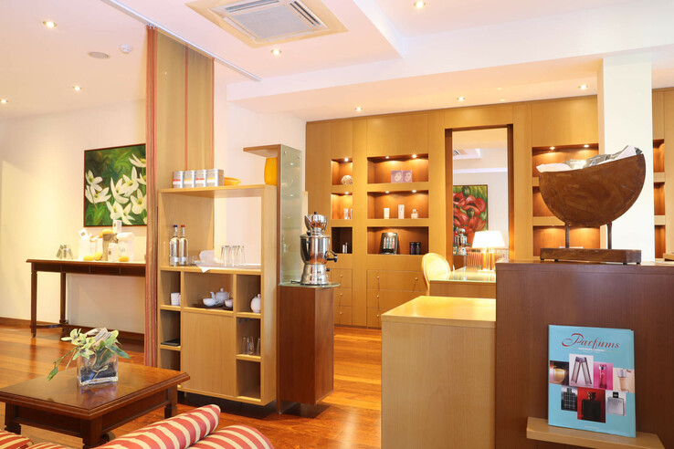 Elegante Hotel-Lounge mit Holzmöbeln, Kunstwerken und einer Auswahl an Getränken und Snacks auf Regalen.