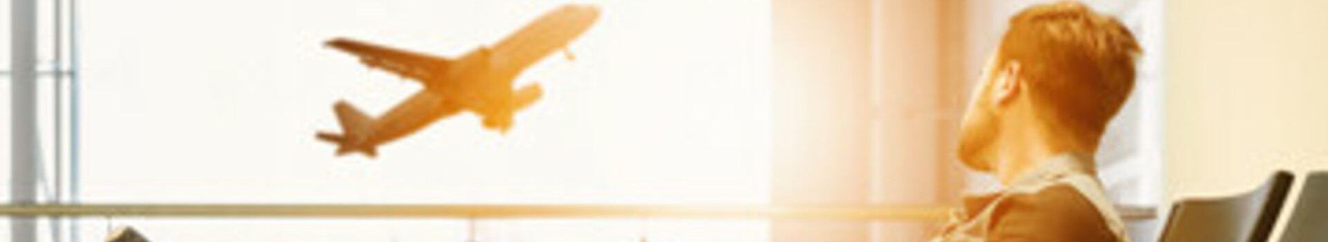 Mann schaut Flugzeug nach A man relaxes in the airport terminal, watching an airplane take off.