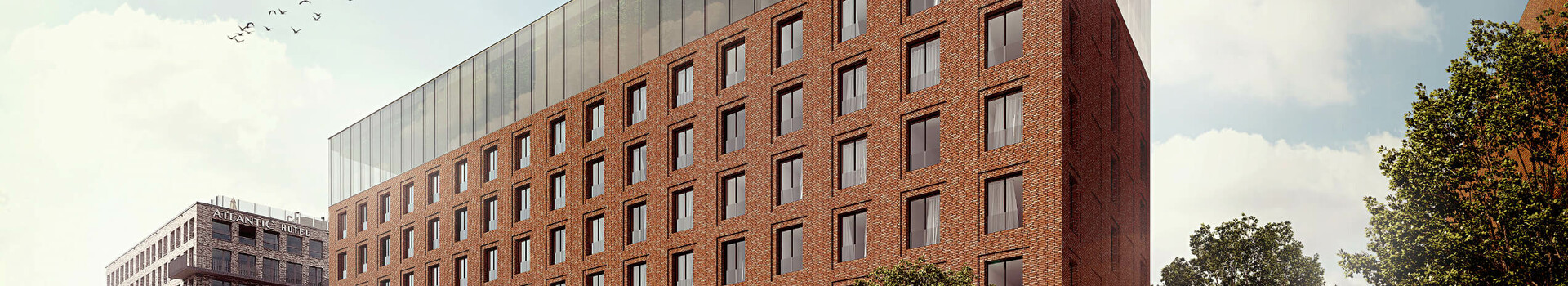 Brick hotel building with large windows, trees in front and people on the sidewalk in daylight.