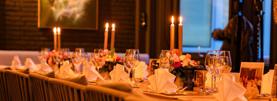 Festlich eingedeckte Tafel mit Blumen und Kerzen im Wintergarten.
