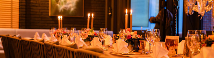 Festlich eingedeckte Tafel mit Blumen und Kerzen im Wintergarten.