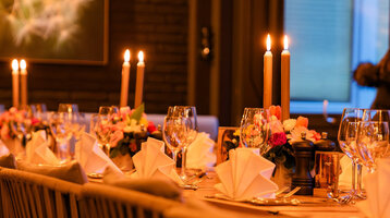 Festlich eingedeckte Tafel mit Blumen und Kerzen im Wintergarten.