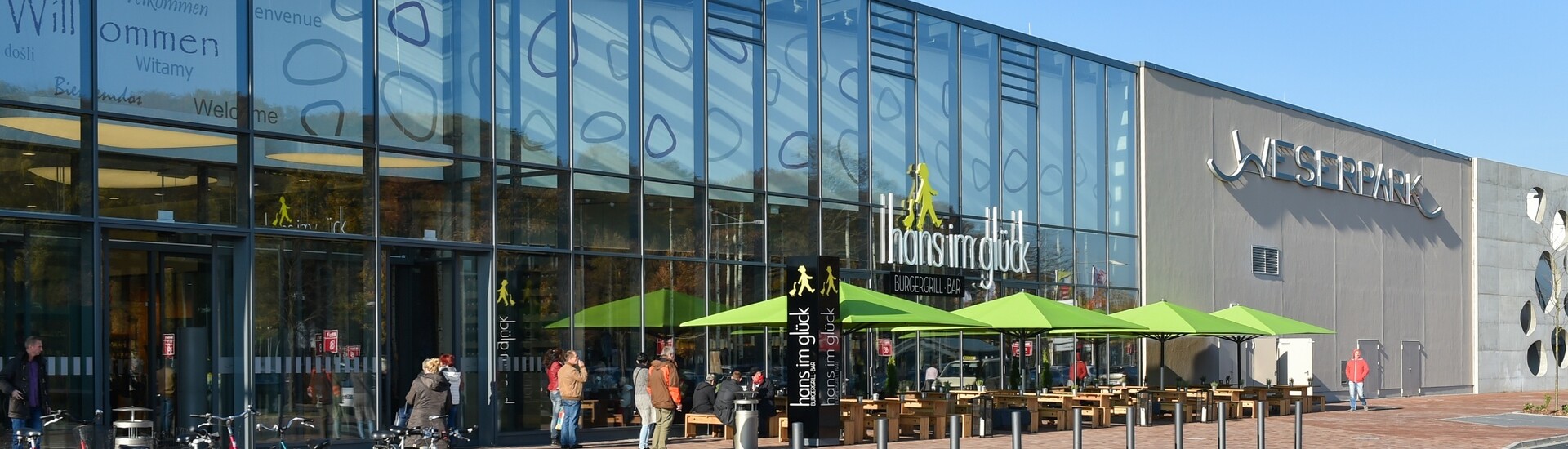 Blick auf das Einkaufzentrum Weserpark in Bremen Moderne Glasfassade des Weserparks in Bremen mit Außensitzbereich und Fahrradständern.