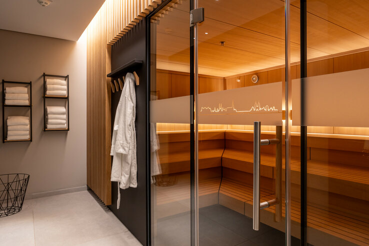 Moderner Saunabereich im ATLANTIC Hotel Heidelberg mit Holzinterieur, Handtüchern und Bademantel.