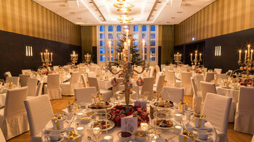 Elegant ballroom in the ATLANTIC Grand Hotel Bremen, festively laid tables with candlesticks and gifts.