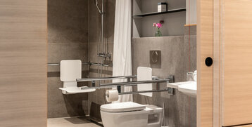 Barrierefreies Badezimmer im ATLANTIC Hotel Heidelberg mit Haltegriffen, Duschsitz und moderner Ausstattung.