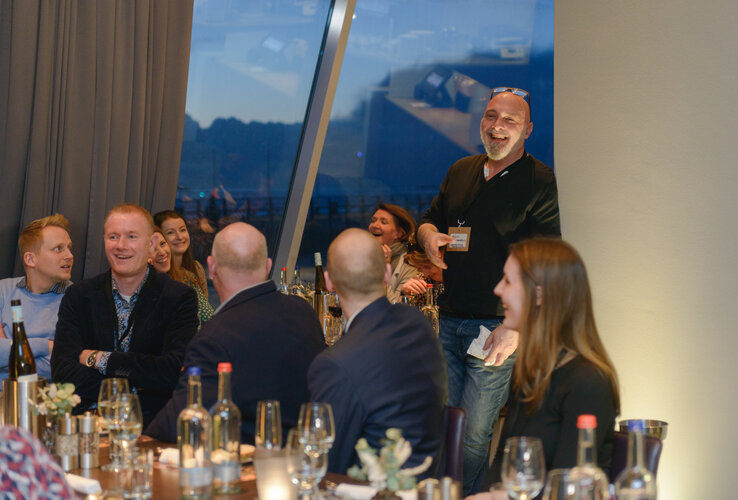 Group of people laughing and chatting over dinner at the ATLANTIC Hotel Sail City, Bremerhaven.