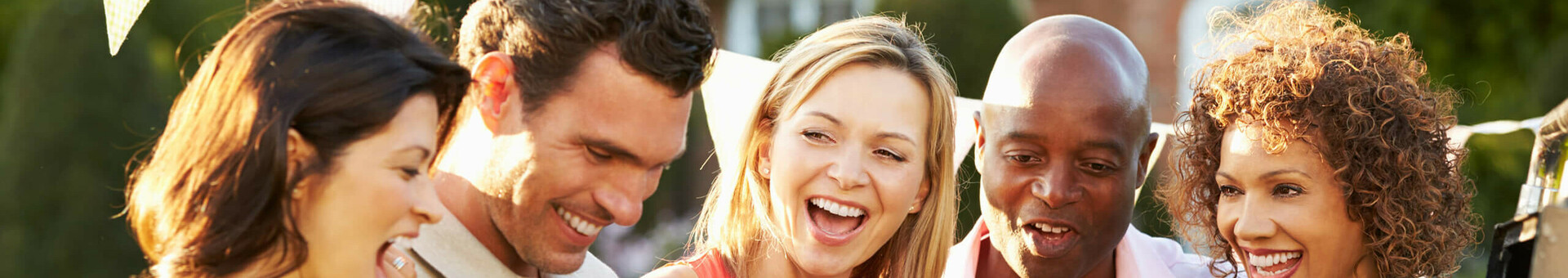 Sommerfest mit BBQ im Garten des ATLANTIC Hotel Galopprennbahn in Bremen Gruppe fröhlicher Menschen bei Grillparty im Freien, mit Getränken und Essen, unter Wimpelgirlande.