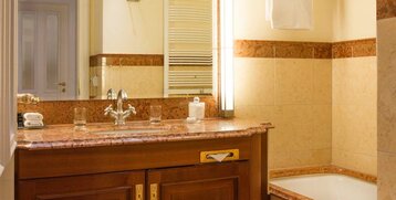 Elegant bathroom with marble washbasin, mirror, bathtub and towel rail at the ATLANTIC Grand Hotel Travemünde.