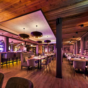 Gemütliches Hotelrestaurant mit warmem Holzinterieur, gedeckten Tischen und stimmungsvoller Beleuchtung.