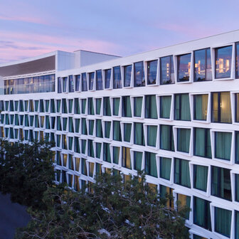 Das ATLANTIC Hotel Münster Aussenfassade bei Nacht mit lila Wolken