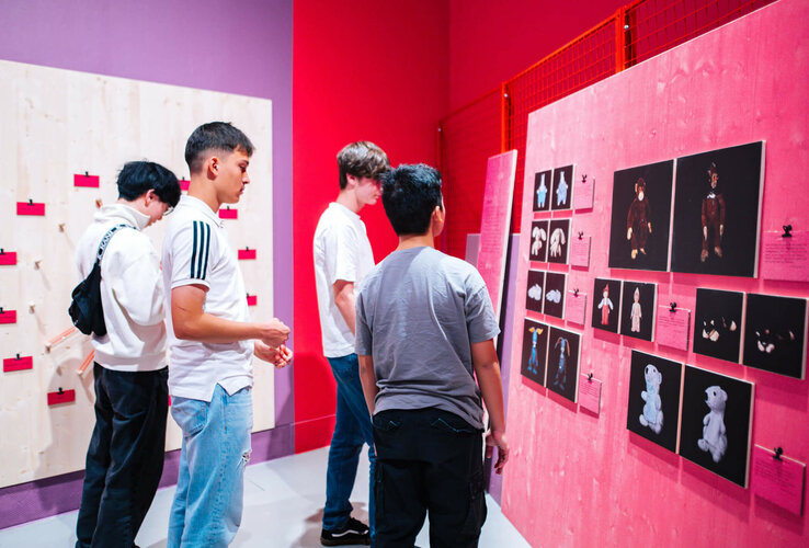 Besucher betrachten bunte Ausstellungswände mit Bildern in einem modernen Museum oder Ausstellungsraum.