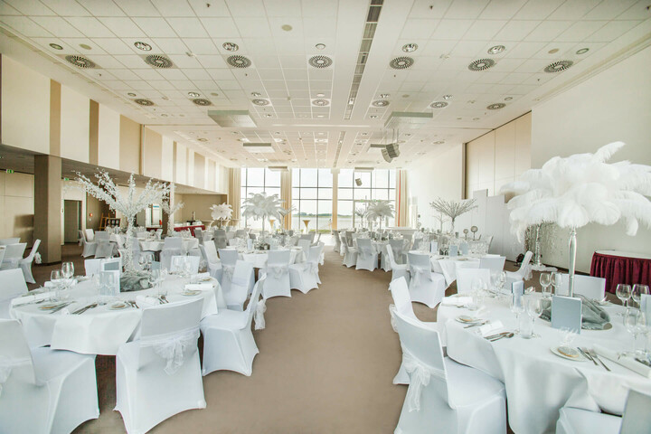 Wedding in the ATLANTIC Hotel Sail City in Bremerhaven Elegant banquet hall in the ATLANTIC Hotel Sail City, Bremerhaven, with white-clothed tables and large windows.