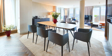Bright suite in the ATLANTIC Grand Hotel Bremen with dining table, modern chairs, large windows and stylish furnishings.