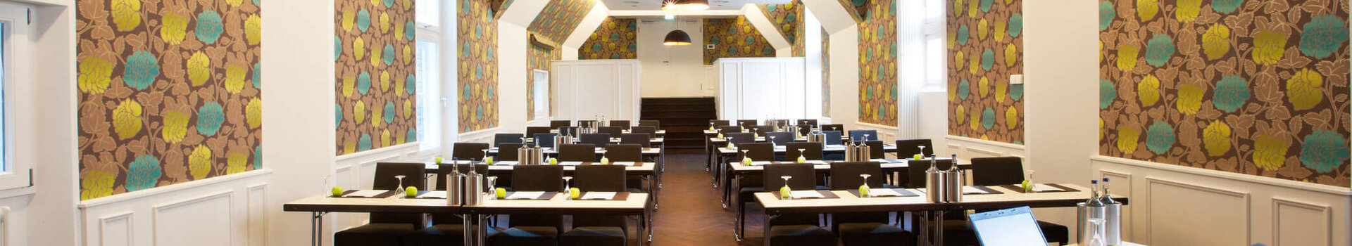 Modern conference room in the ATLANTIC Grand Hotel Bremen with stylish wallpaper and rows of tables.