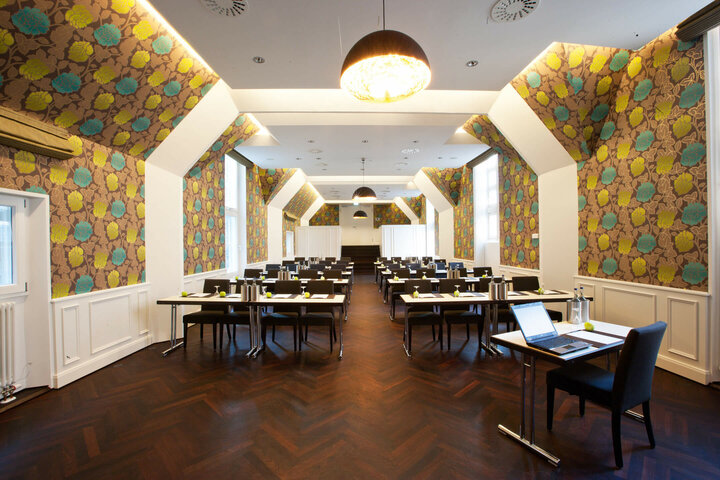 Modern conference room in the ATLANTIC Grand Hotel Bremen with stylish wallpaper and rows of tables.