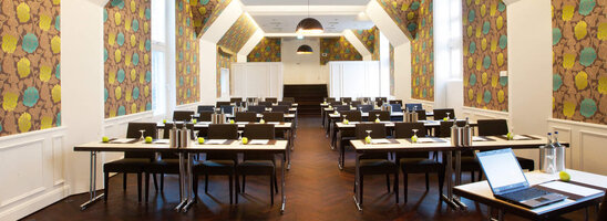 Modern conference room in the ATLANTIC Grand Hotel Bremen with stylish wallpaper and rows of tables.