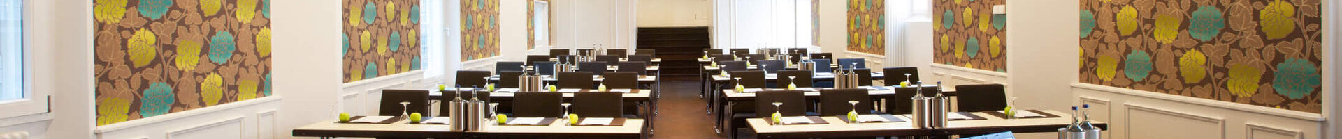 Modern conference room in the ATLANTIC Grand Hotel Bremen with stylish wallpaper and rows of tables.