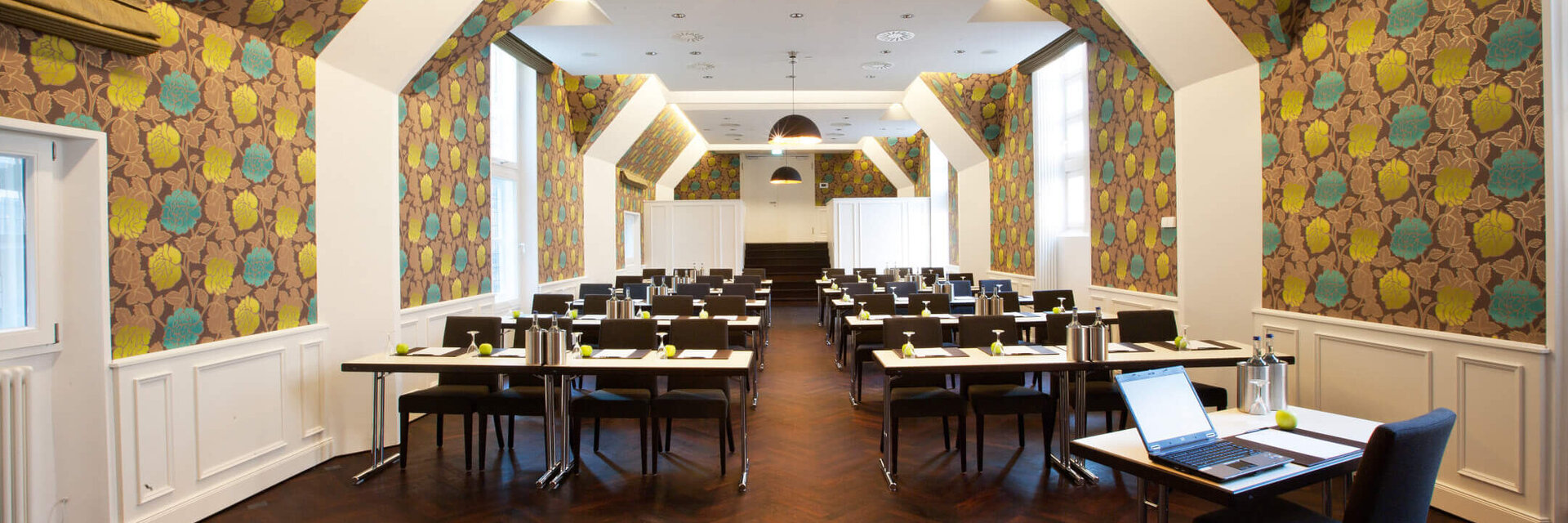 Modern conference room in the ATLANTIC Grand Hotel Bremen with stylish wallpaper and rows of tables.