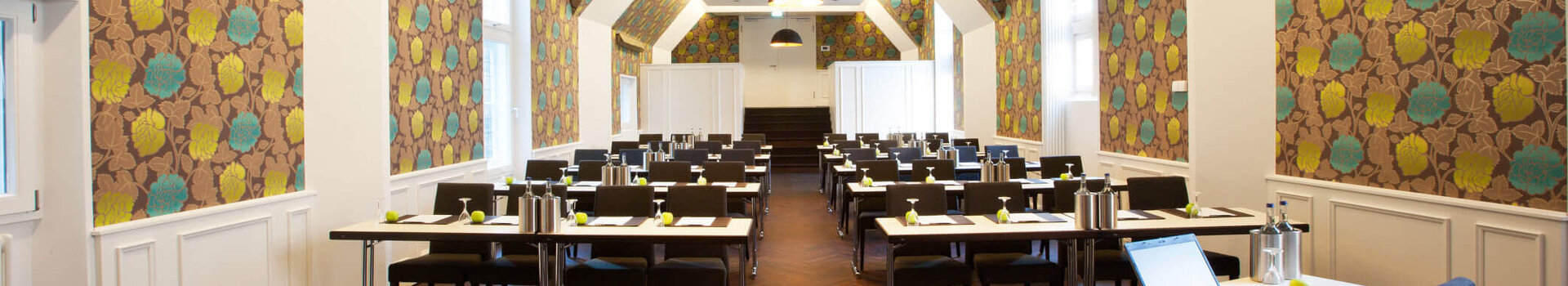 Moderner Konferenzraum im ATLANTIC Grand Hotel Bremen mit stilvoller Tapete und Tischen in Reihen.