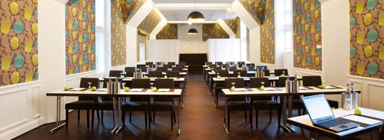 Moderner Konferenzraum im ATLANTIC Grand Hotel Bremen mit stilvoller Tapete und Tischen in Reihen.