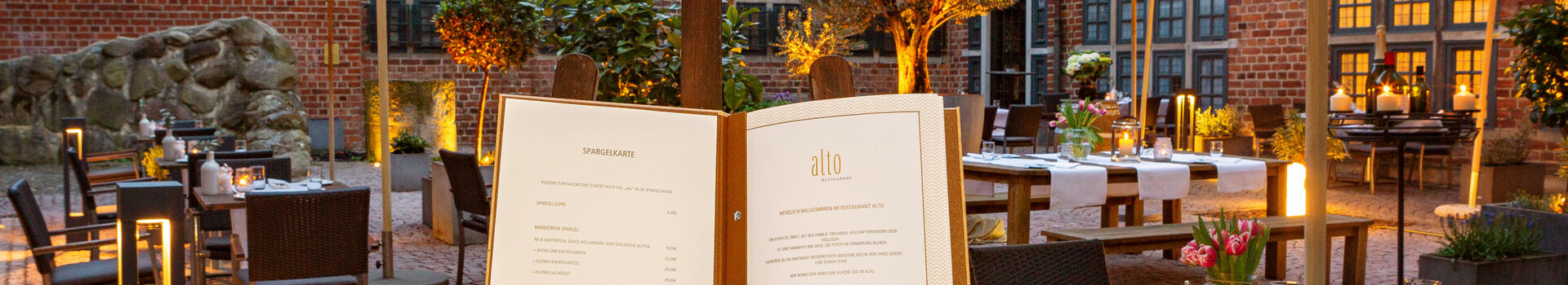Cozy hotel courtyard with covered tables, parasols and atmospheric lighting in the evening.