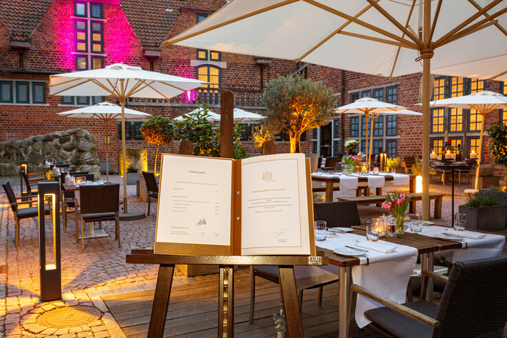Cozy hotel courtyard with covered tables, parasols and atmospheric lighting in the evening.