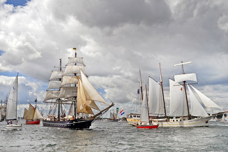 Sailing ships on the Kiel Fjord under a cloudy sky, maritime flair.
